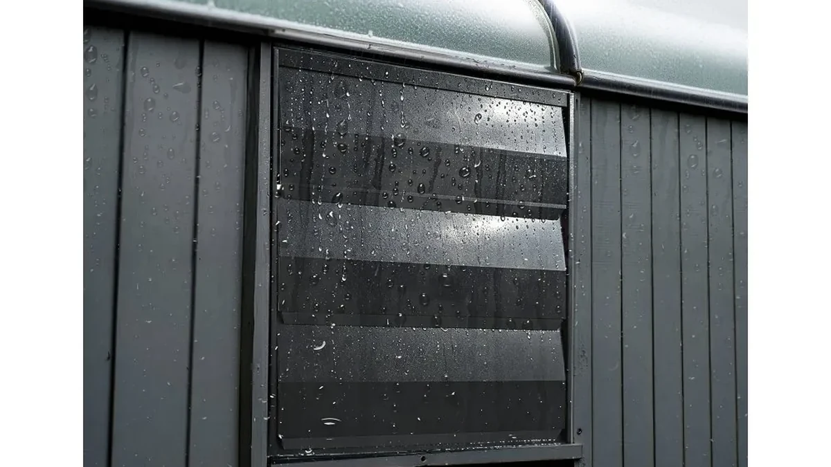 Wall-mounted louvered exhaust fan vent with rain droplets